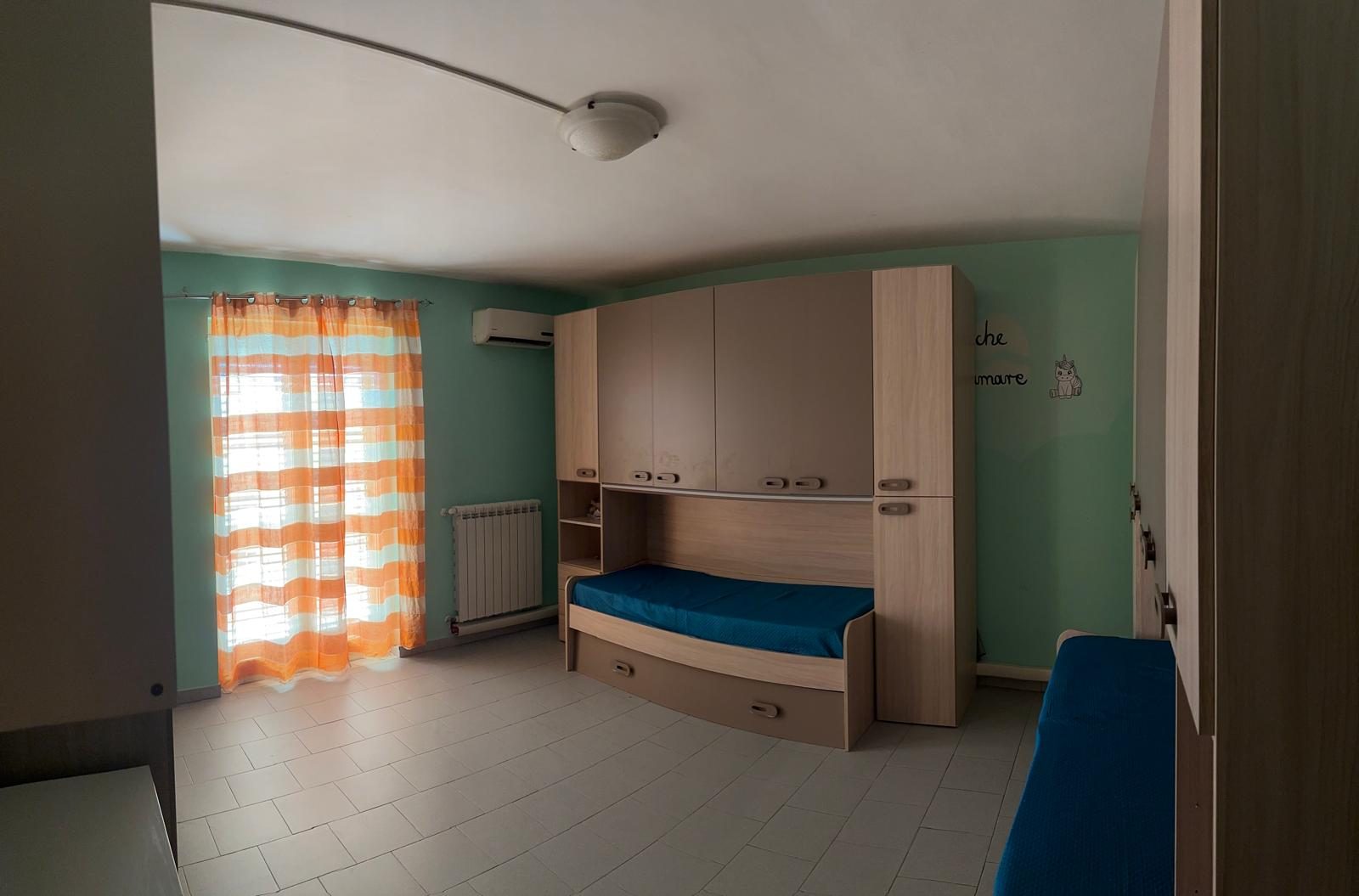 Cameretta con letto singolo, lettino e armadio nella comunità Casa Mia