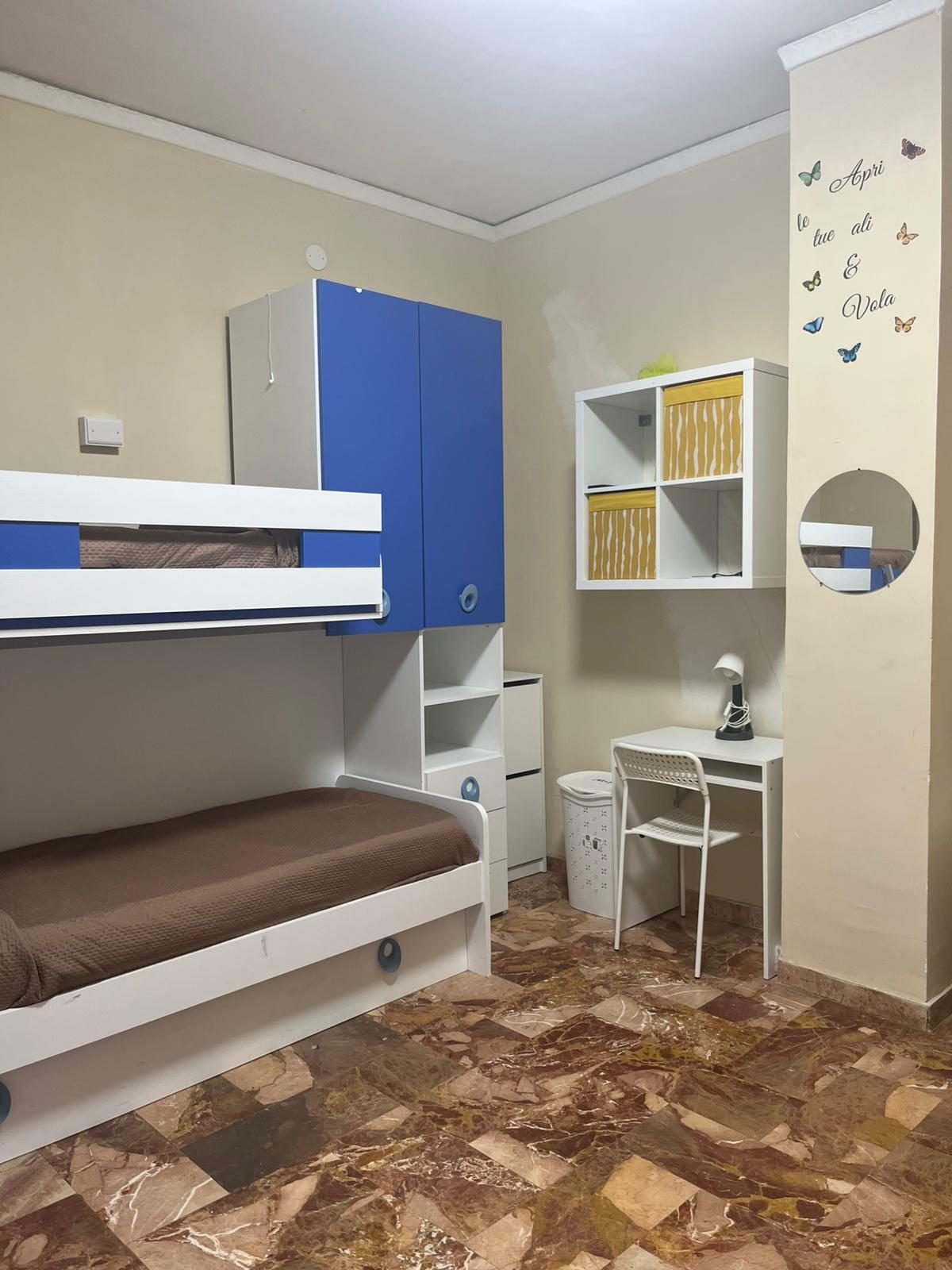 Cameretta con letto a castello blu e scritta “Apri le tue ali e vola” nella comunità Namasté